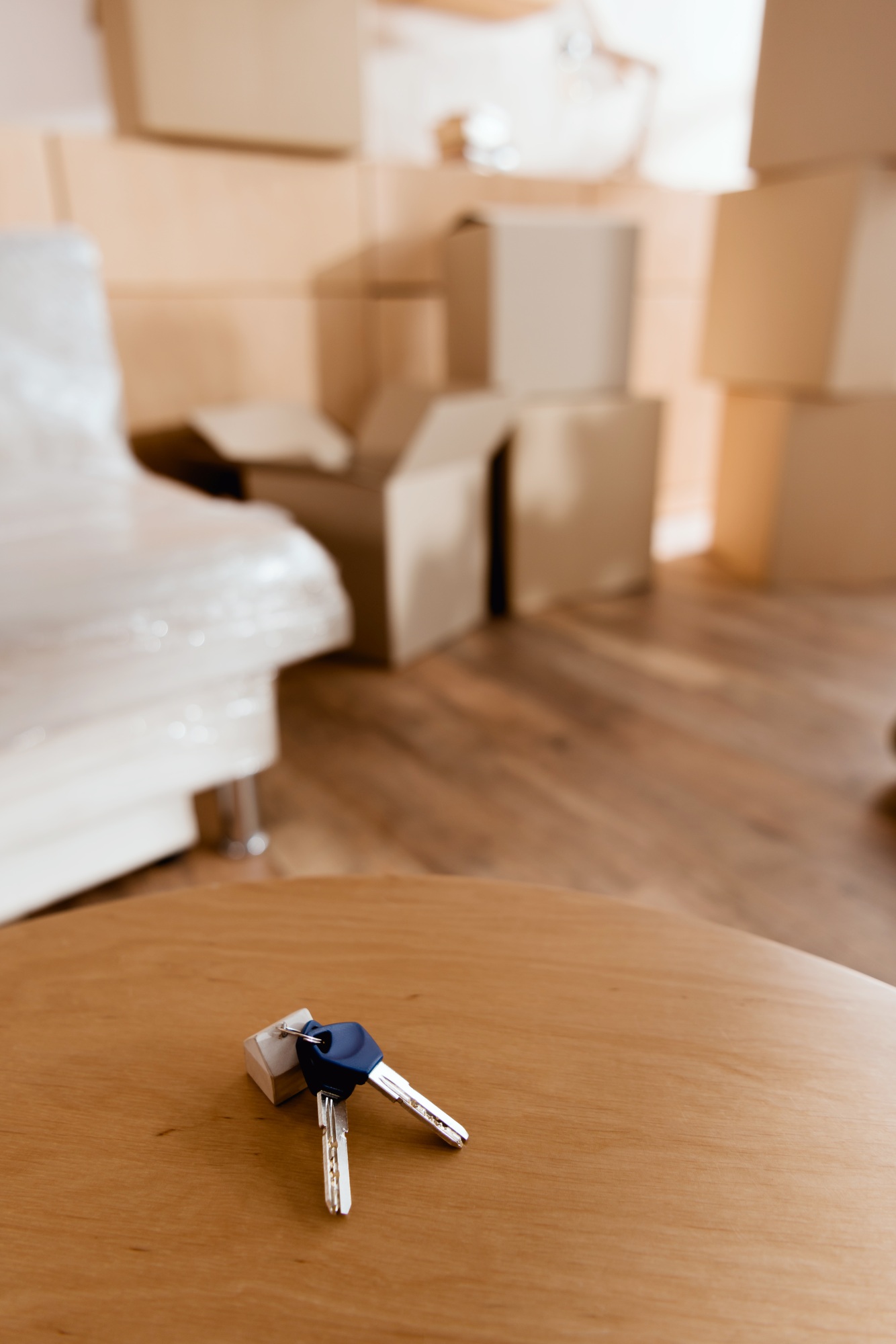 keys on table in new apartment with cardboard boxes, moving concept